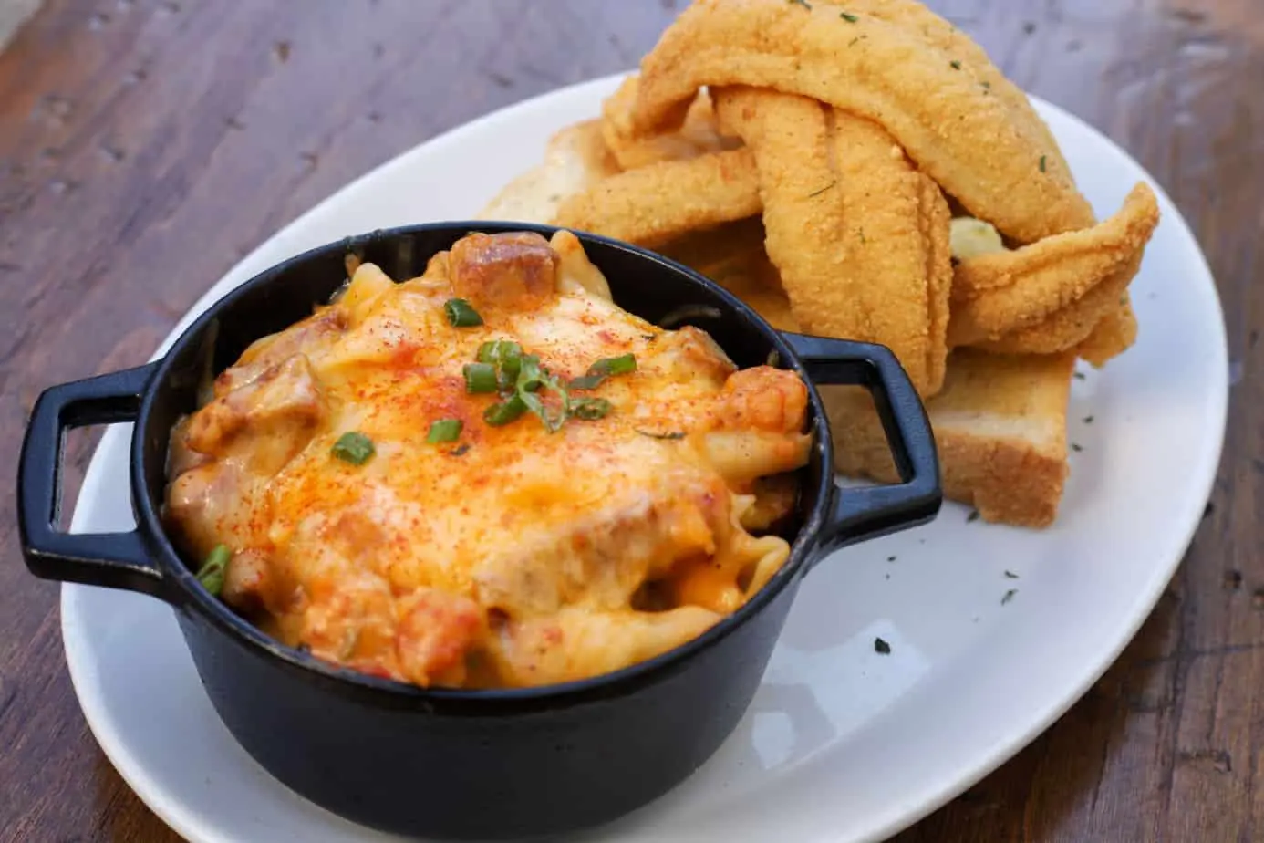 Baked mac and cheese in a cast iron pot with fried fish and toast